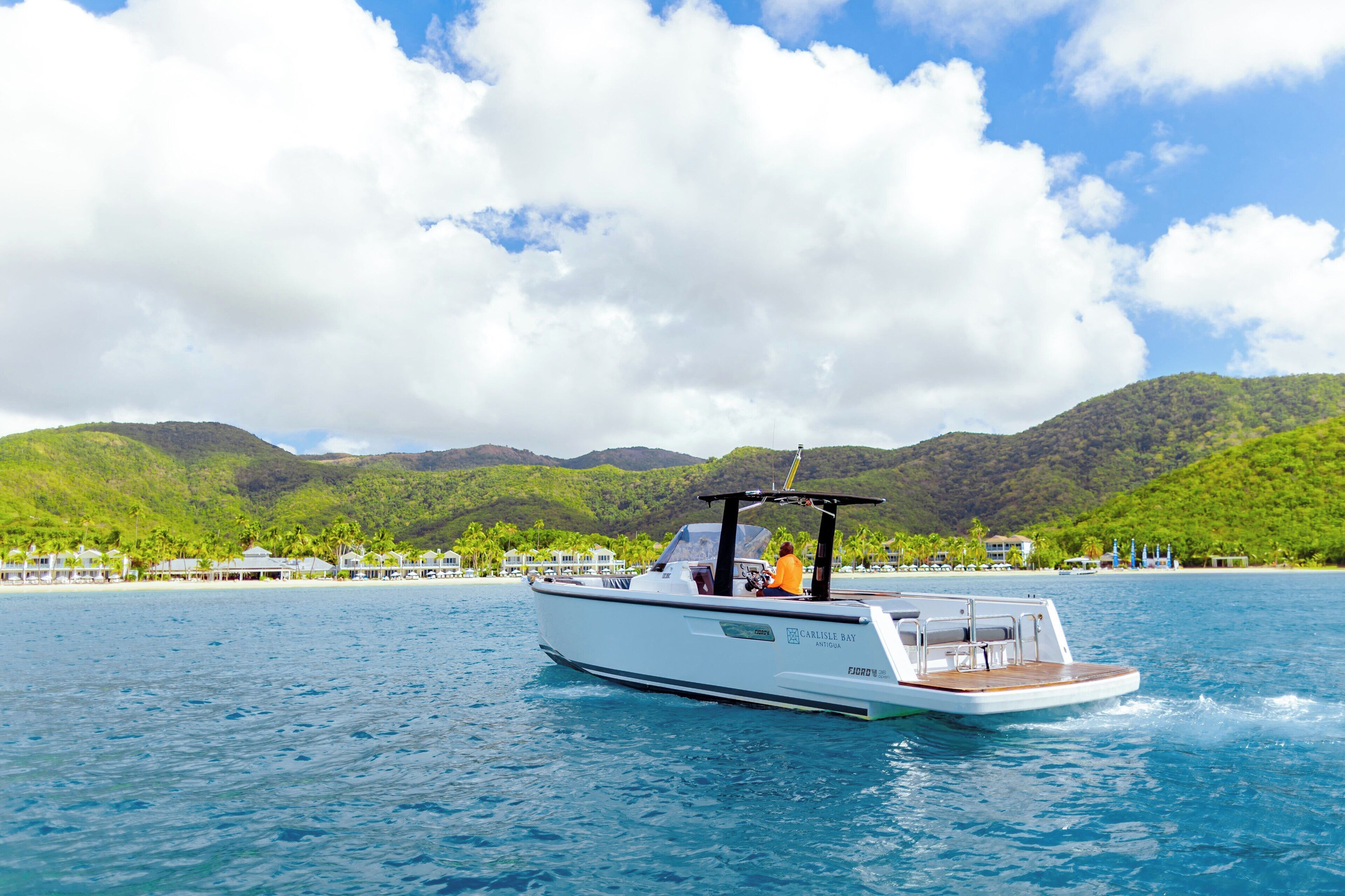 A boat on a calm sea with a backdrop of green hills and a clear sky.