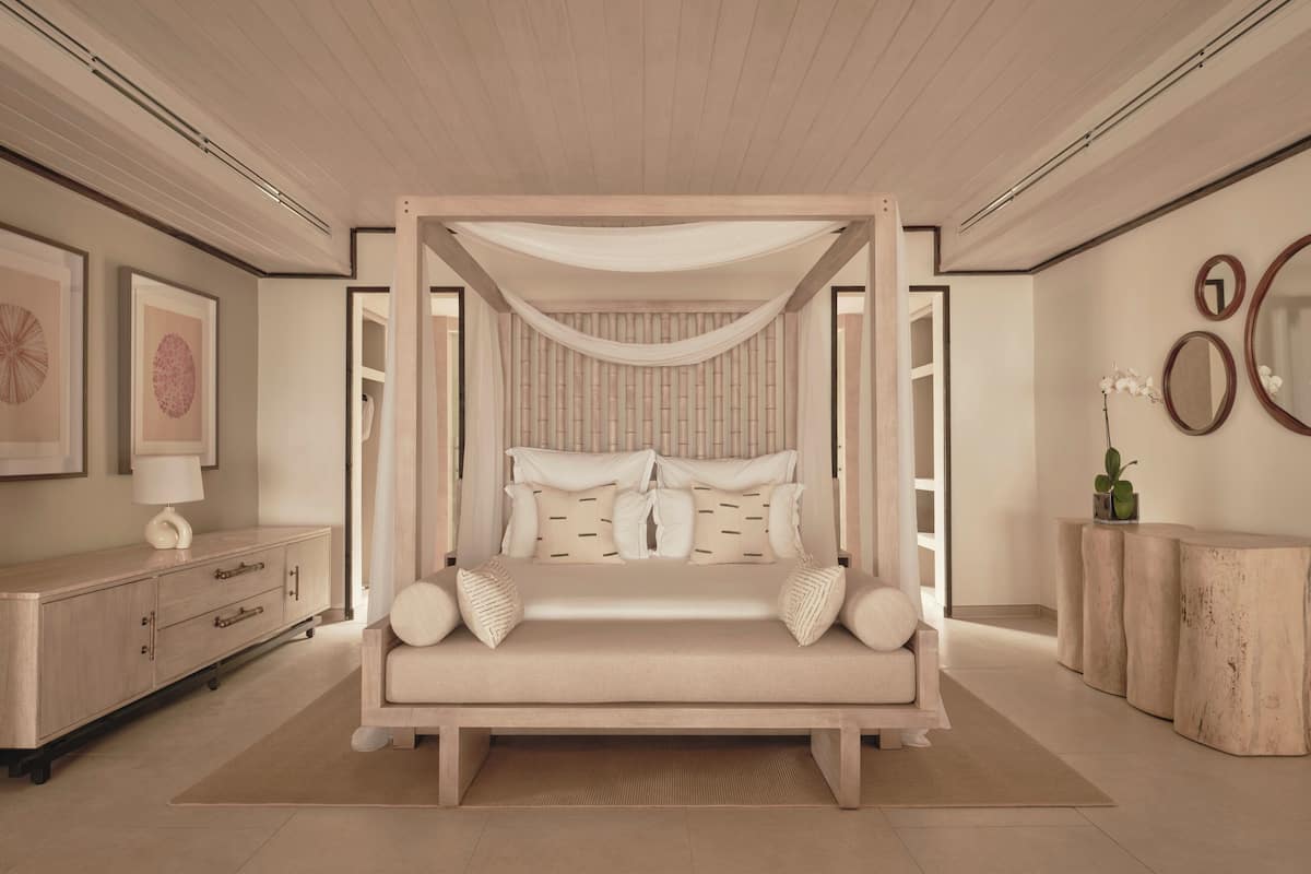 A bedroom with a canopy bed, a wooden dresser, and a mirror on the wall.