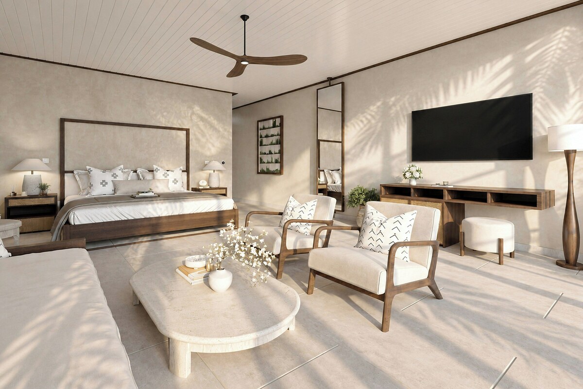 A modern bedroom with a large bed, a ceiling fan, a flat-screen TV, and a seating area with a coffee table and chairs.