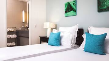 A hotel room with a bed, a nightstand, a lamp, and artwork on the wall.
