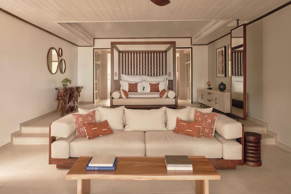 A modern living room with a sofa, a coffee table, a ceiling fan, and a large mirror.