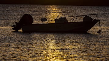 A boat named "RECARLIS BAY 1" on calm water during sunset.