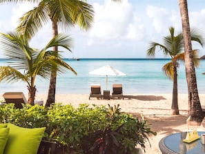 A beach with palm trees, a white umbrella, and two lounge chairs. - Carlisle Bay (Carlisle Bay)