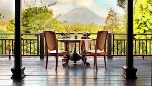 A wooden deck with a table and chairs, overlooking a mountainous landscape with lush greenery. - MesaStila Resort and Spa (Pringsurat)