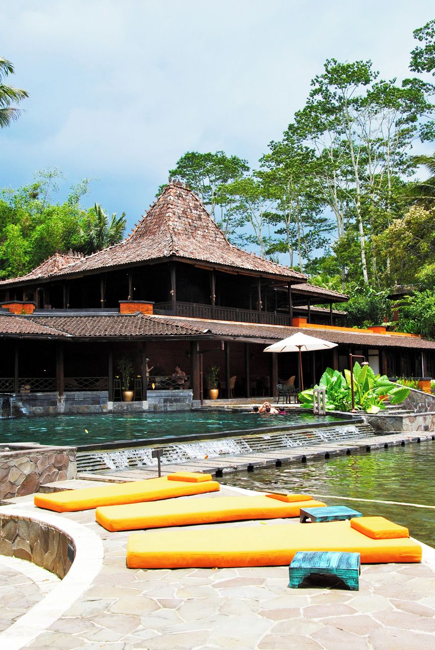 Resort com piscina, área de estar externa e edifício tradicional com telhado de palha.