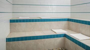 Un baño con azulejos blancos y azules, un banco y un piso de mosaico.
