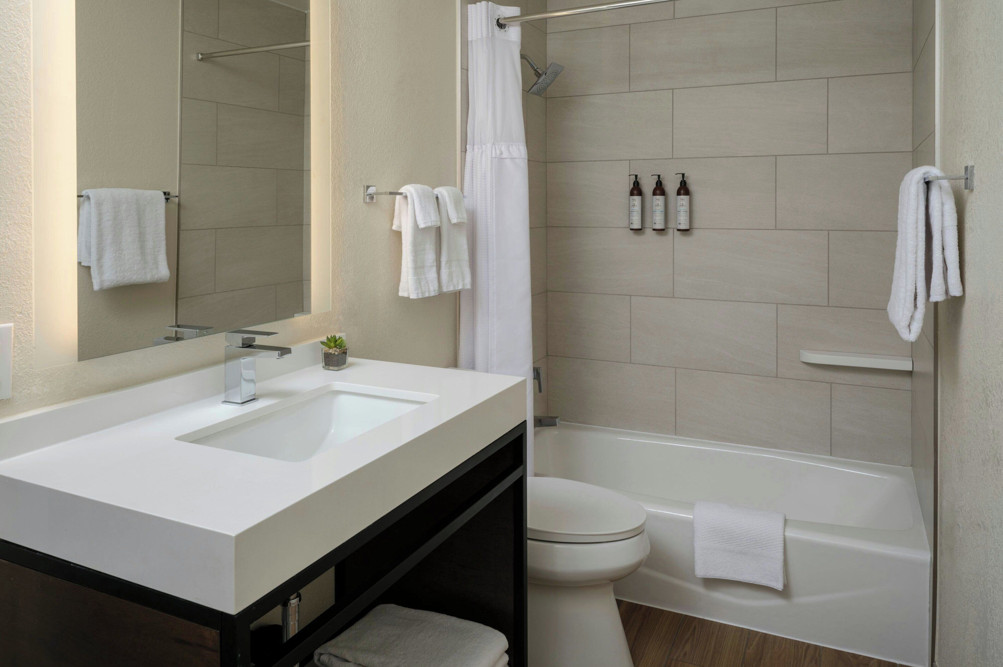 Een moderne badkamer met twee wastafels, een toilet en een bad.