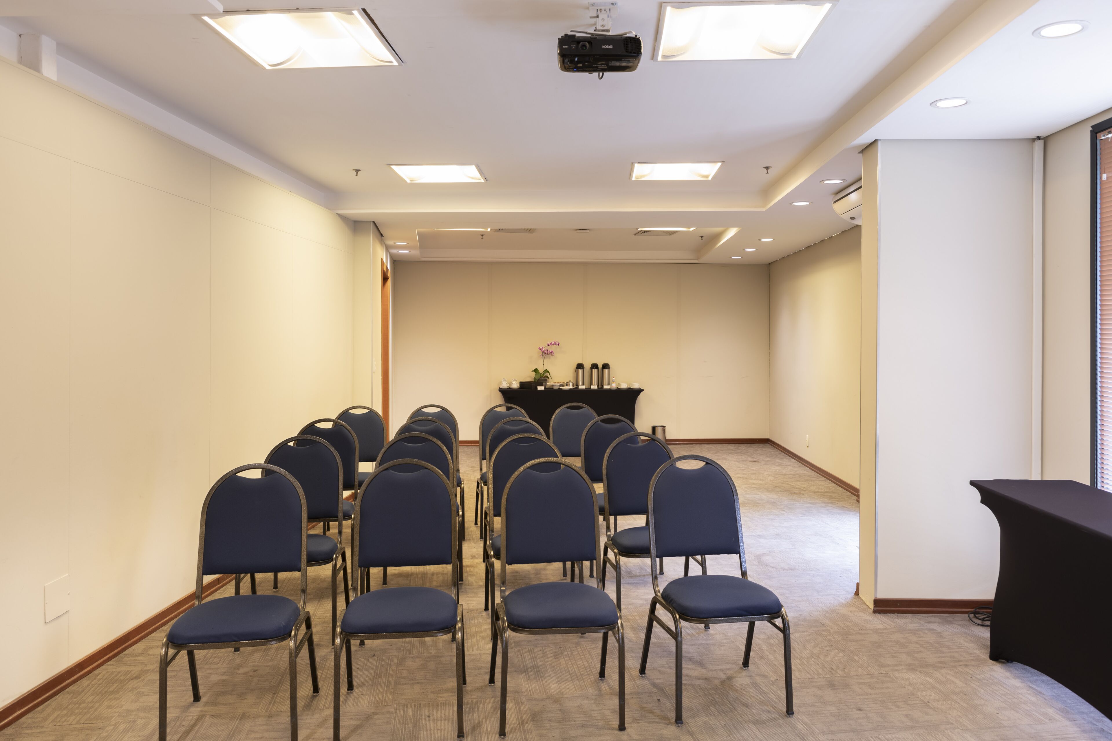 Ein Konferenzraum mit Reihen von Stühlen, einem Rednerpult und einem Projektor an der Decke.