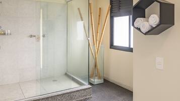 A modern bathroom with a glass shower enclosure, a bamboo stick holder, and a towel rack.