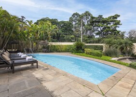 Una piscina al aire libre, sillones reclinables de piscina