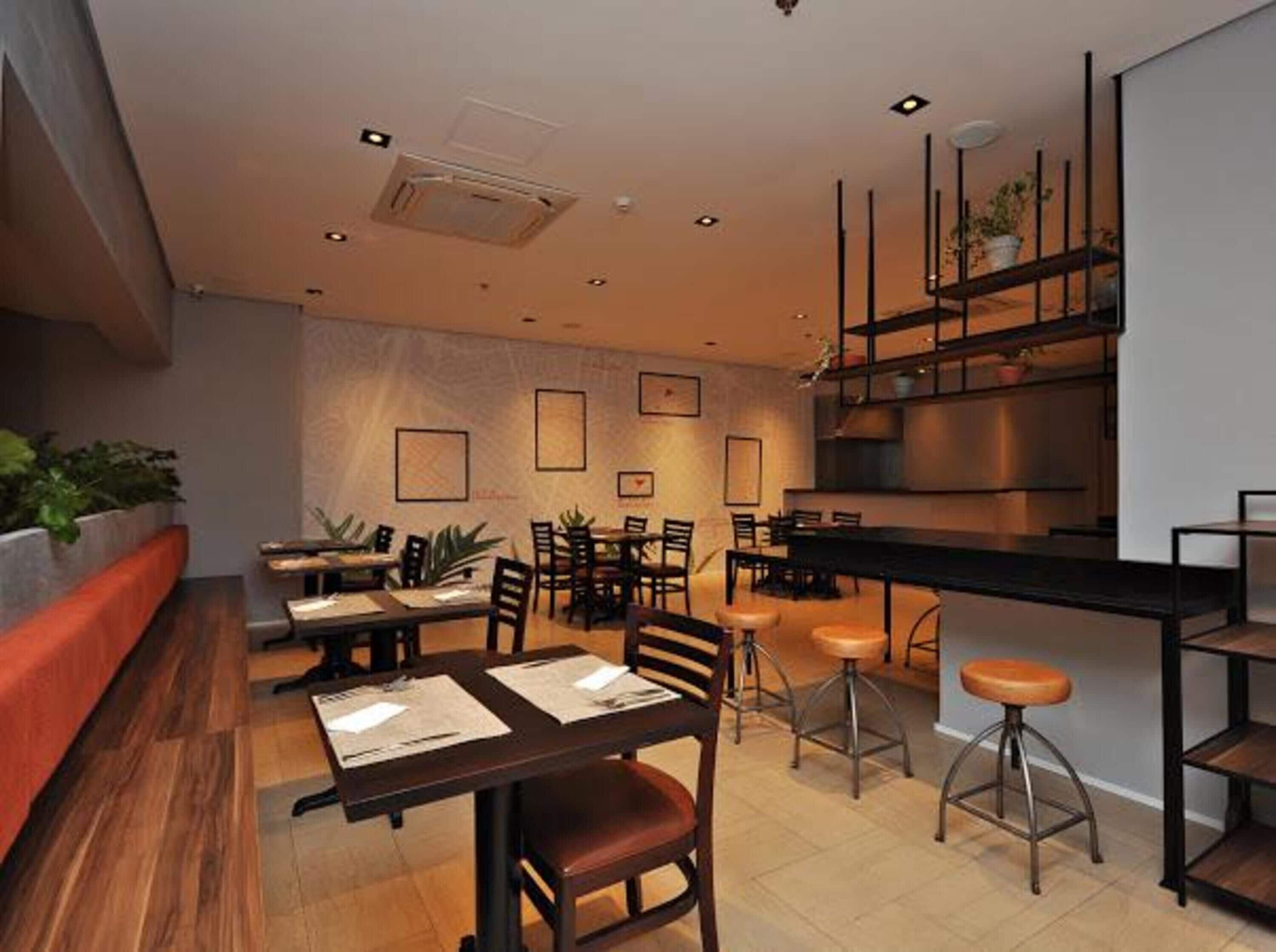 Een modern restaurantinterieur met houten tafels, metalen stoelen en een bar.