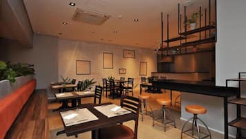 Een modern restaurantinterieur met houten tafels, metalen stoelen en een bar.