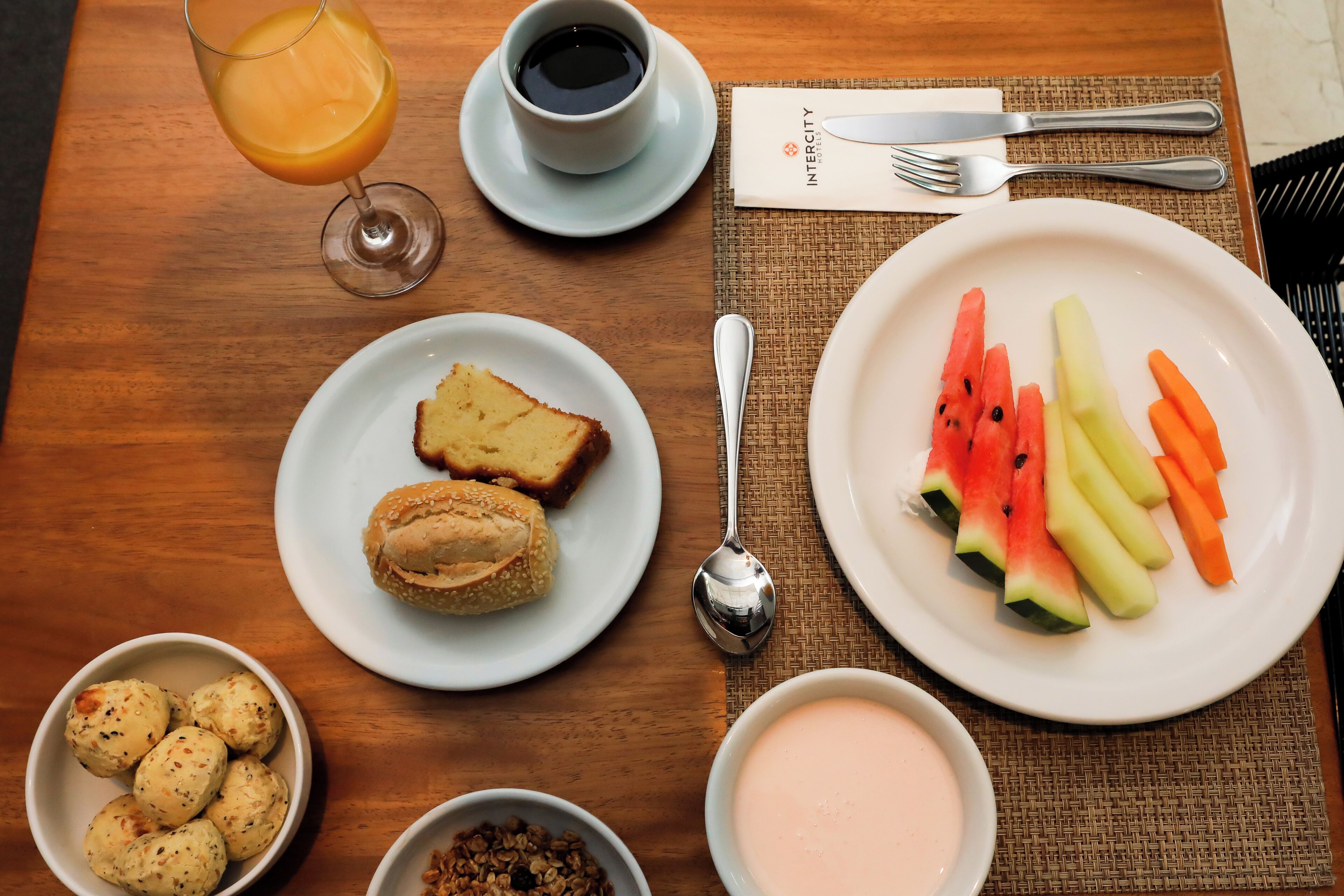Ein Frühstückstisch mit Toast, Croissants, Obst und einem Glas Orangensaft.