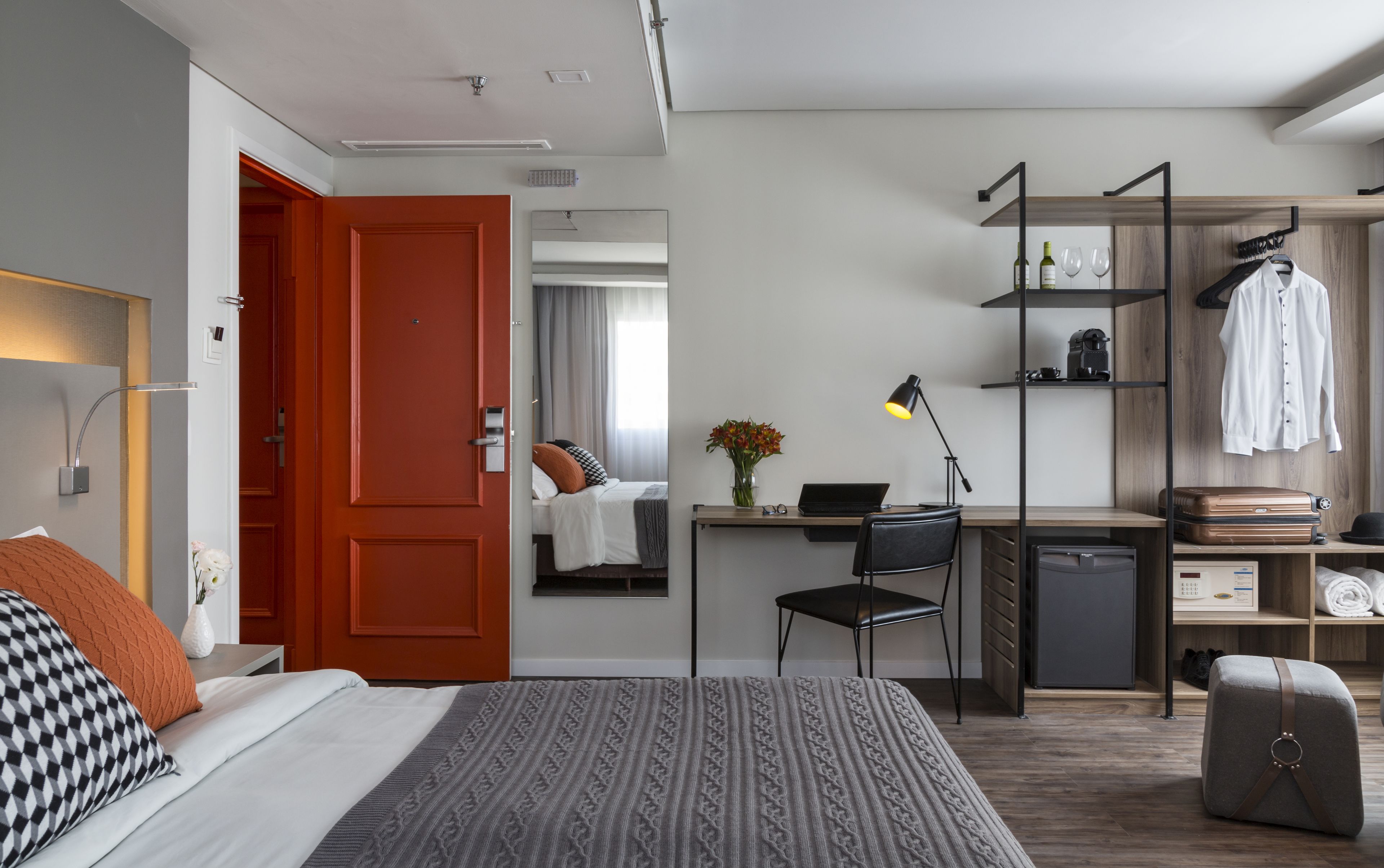 Une chambre d’hôtel moderne équipée d’un lit, d’un bureau, d’une chaise et d’une armoire.