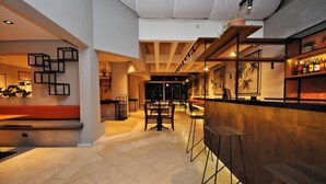 Ein moderner Barbereich mit hoher Decke, sichtbaren Balken und einer Bar mit Hockern.