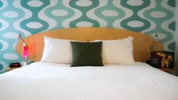 A bed with a wooden headboard, two pillows, a night lamp, and a sign with illuminated letters.