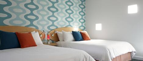 Una habitación de hotel con dos camas, un papel tapiz estampado y una mesita con una lámpara.