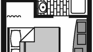 Ein Zimmer mit Bett, Schreibtisch, Stuhl, Fenster und eigenem Badezimmer.