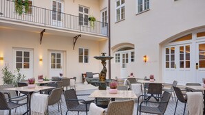 A courtyard with outdoor seating, a fountain, and a balcony with hanging plants. - Boutique Hotel BOOKQUET (Prague)