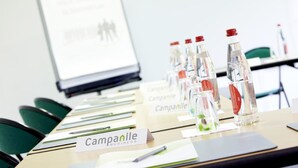 A conference table with water bottles, name tags, and a presentation screen in the background. - Campanile Creteil Centre (Creteil)