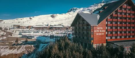 Un hôtel doté d’une enseigne bien visible, situé au cœur d’un paysage montagneux enneigé et à proximité de pistes de ski.