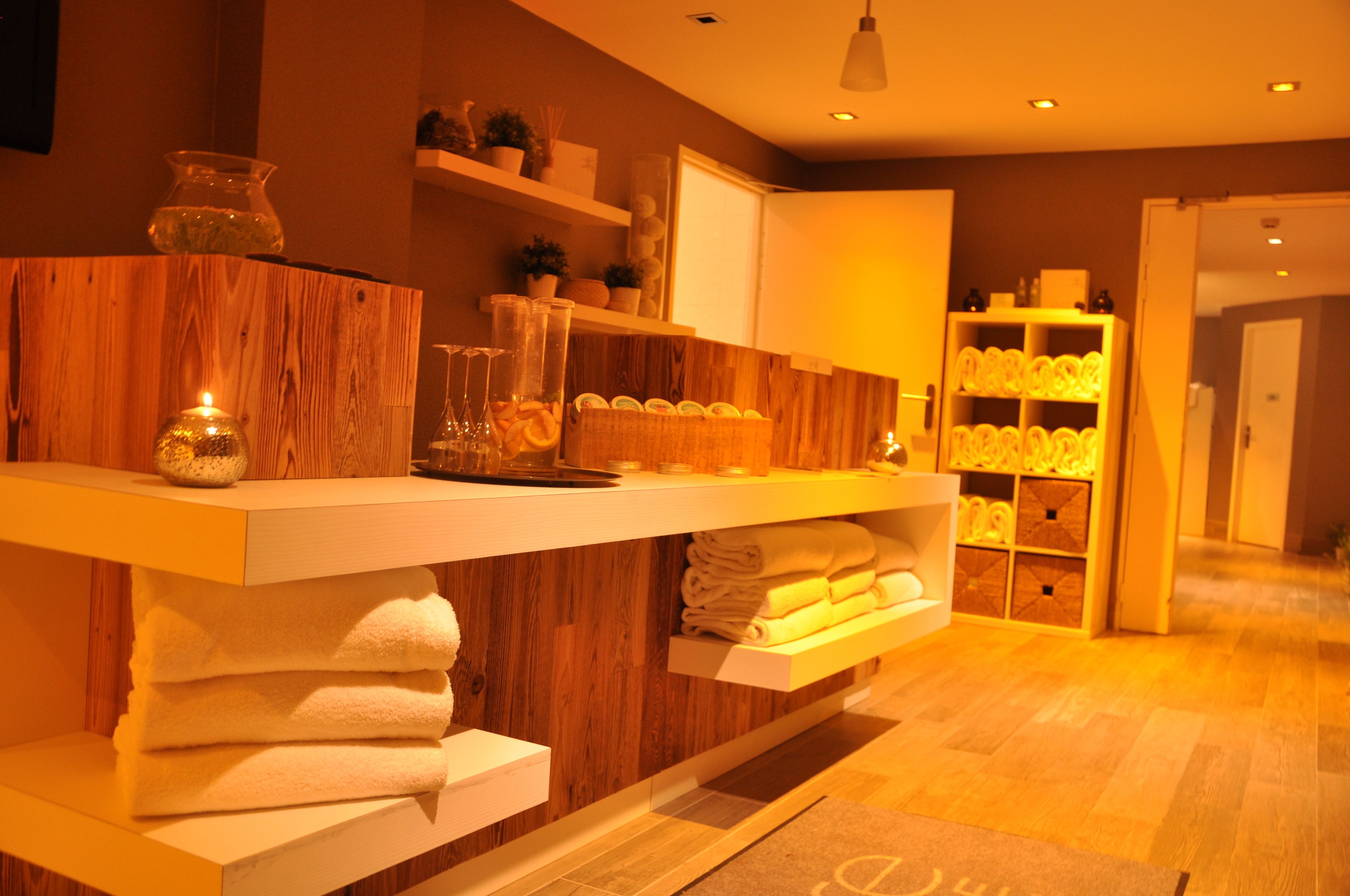 A modern bathroom with wooden accents, a towel rack, and a shelf with toiletries.