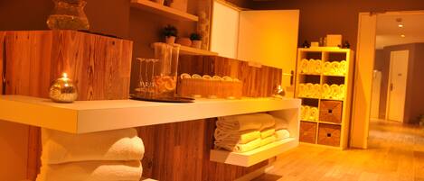 A modern bathroom with wooden accents, a towel rack, and a shelf with toiletries.
