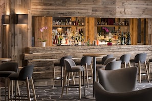 A bar area with wooden walls, multiple liquor bottles, and modern bar stools.
