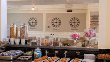 A buffet counter with various food items, including pastries and condiments, and clocks indicating different cities.