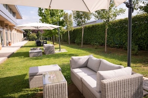 Un espacio al aire libre con patio, un sofá, dos sillas, una mesa y sombrillas.