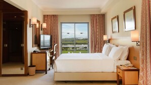 Habitación de hotel con una cama grande, televisión, escritorio y vistas al campo.