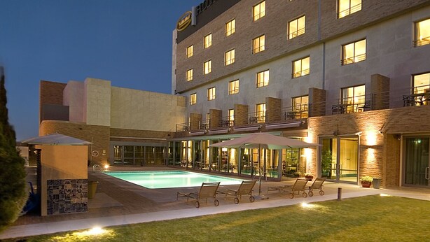Un hotel con piscina, zona de estar al aire libre y fachada iluminada.