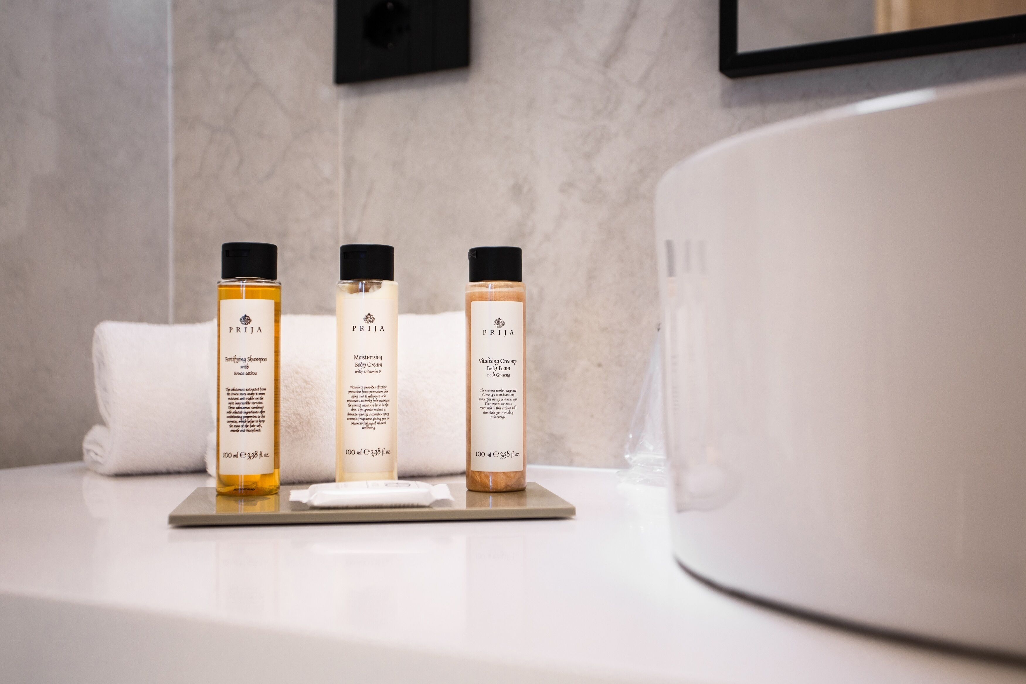 Tres botellas de productos para bebés PRIJIA sobre una encimera de baño.