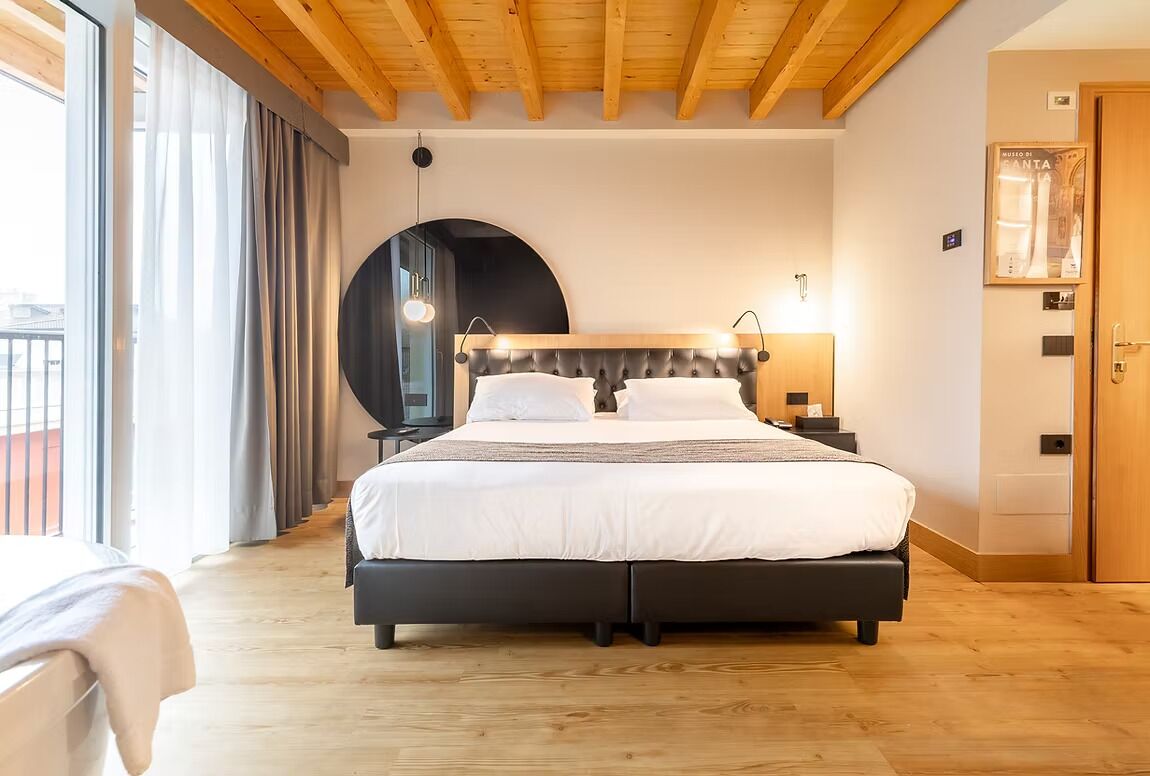Une chambre à coucher avec un lit, un miroir rond, une table de chevet et un plafond en bois.