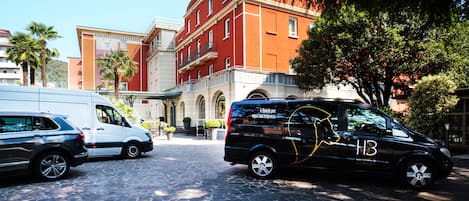 A black van parked on a cobblestone street with a red building in the background.