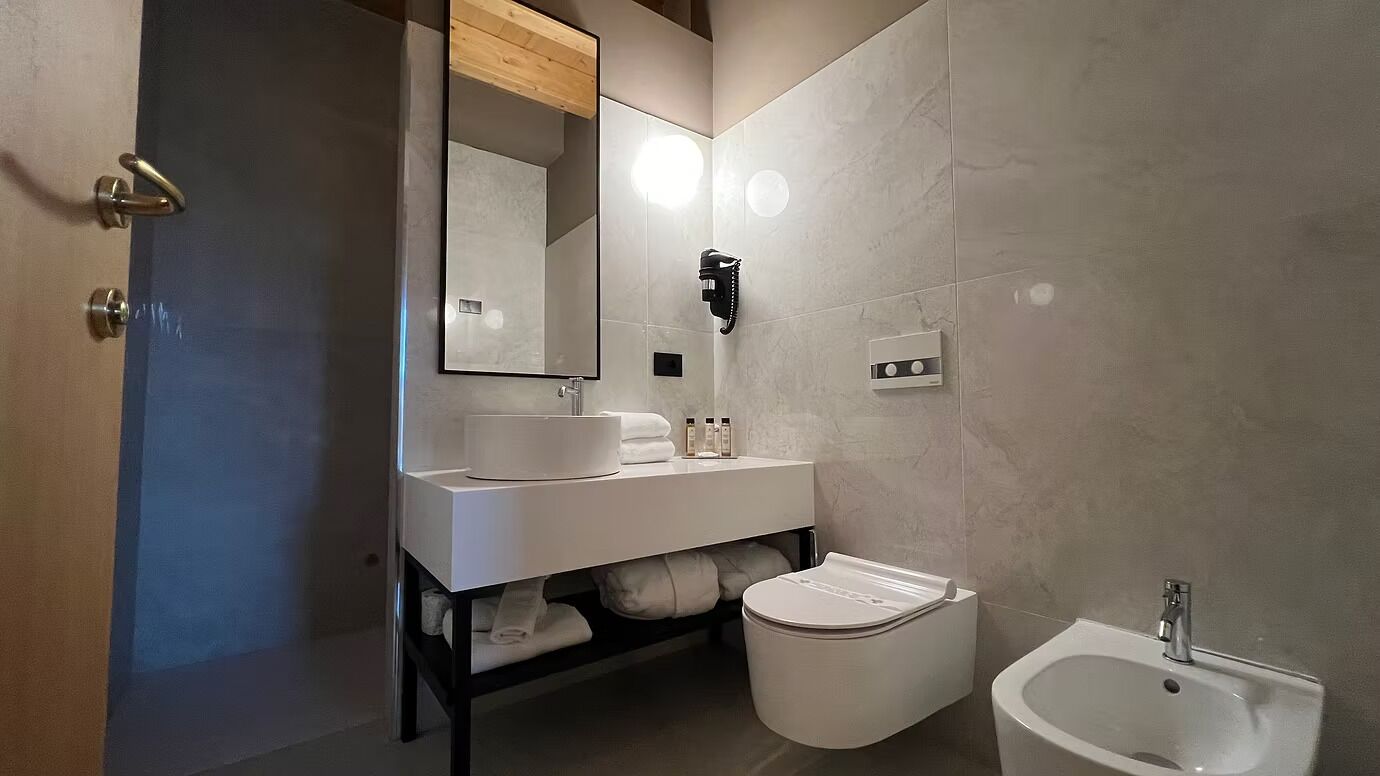 A modern bathroom with a vanity, toilet, bidet, and a large mirror.