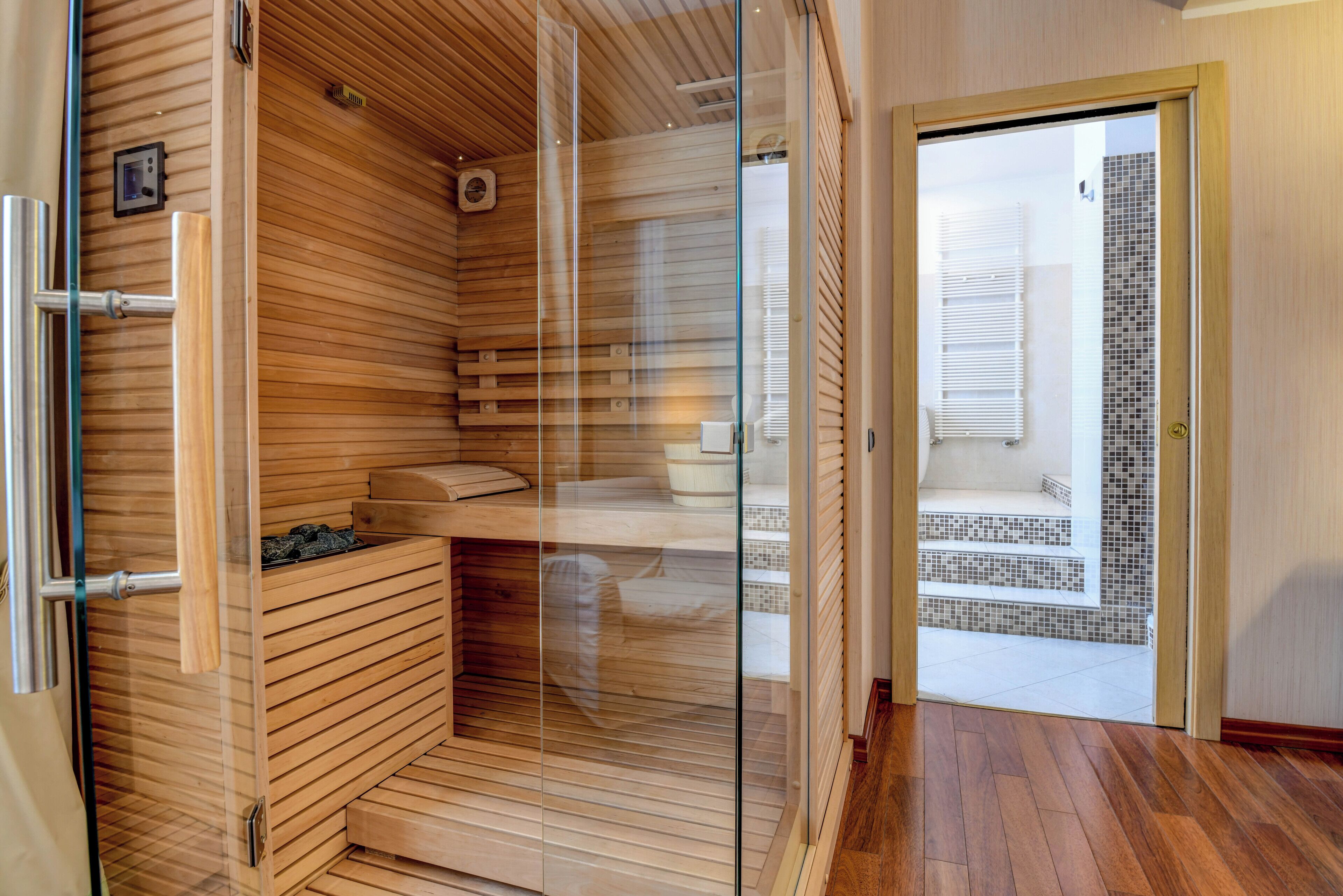 Eine Sauna mit Holzschlittern, einer Glastür und einem gefliesten Boden, der auf einen Balkon führt.
