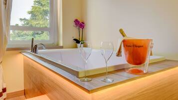 A bathroom with a bathtub, a sink, and a window with a view of trees.