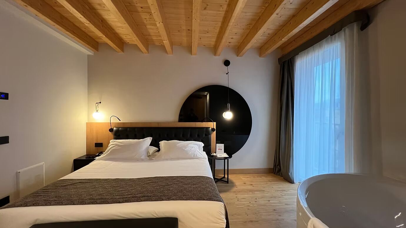 Una camera da letto con un letto, un comodino, una lampada e uno specchio rotondo appeso al muro.
