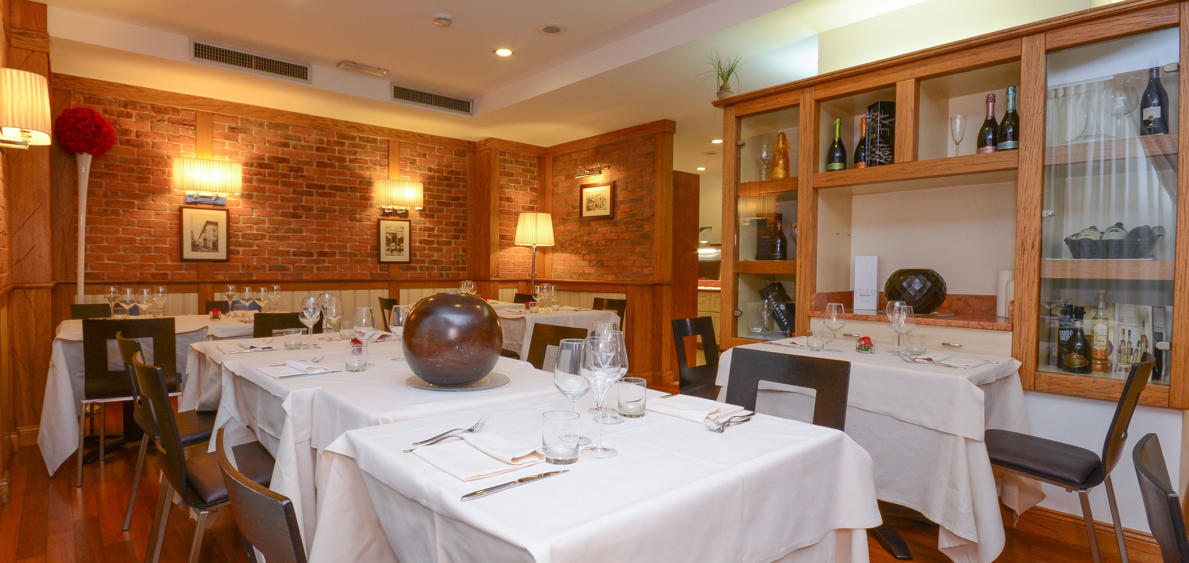 Un restaurante con paredes de ladrillo, manteles blancos y cristalería.