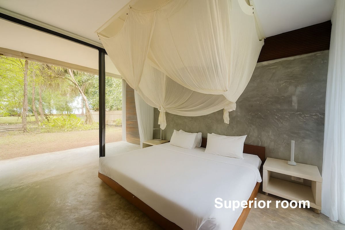 A superior room with a large bed, a nightstand, and a canopy bed.
