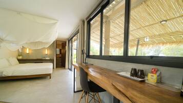 A beachfront view mini suite with a bed, a desk, and a chair.
