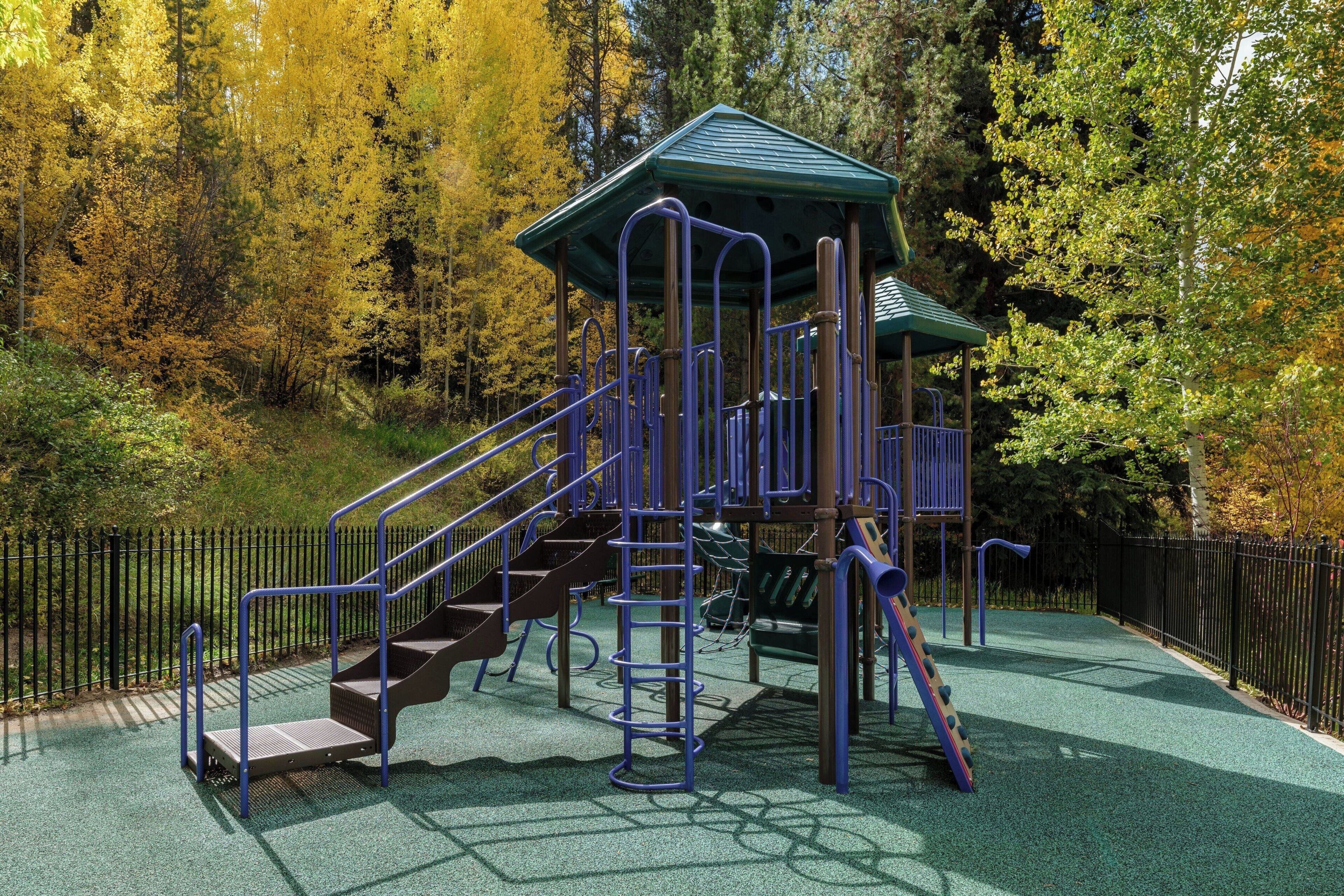 Un parque infantil con techo verde, tobogán y escaleras.