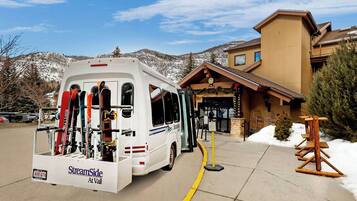 Ein weißer Wohnmobil mit Skiern vor einem Gebäude mit Holzfassade und einem Schild mit der Aufschrift 'StreamSide At Vail'.