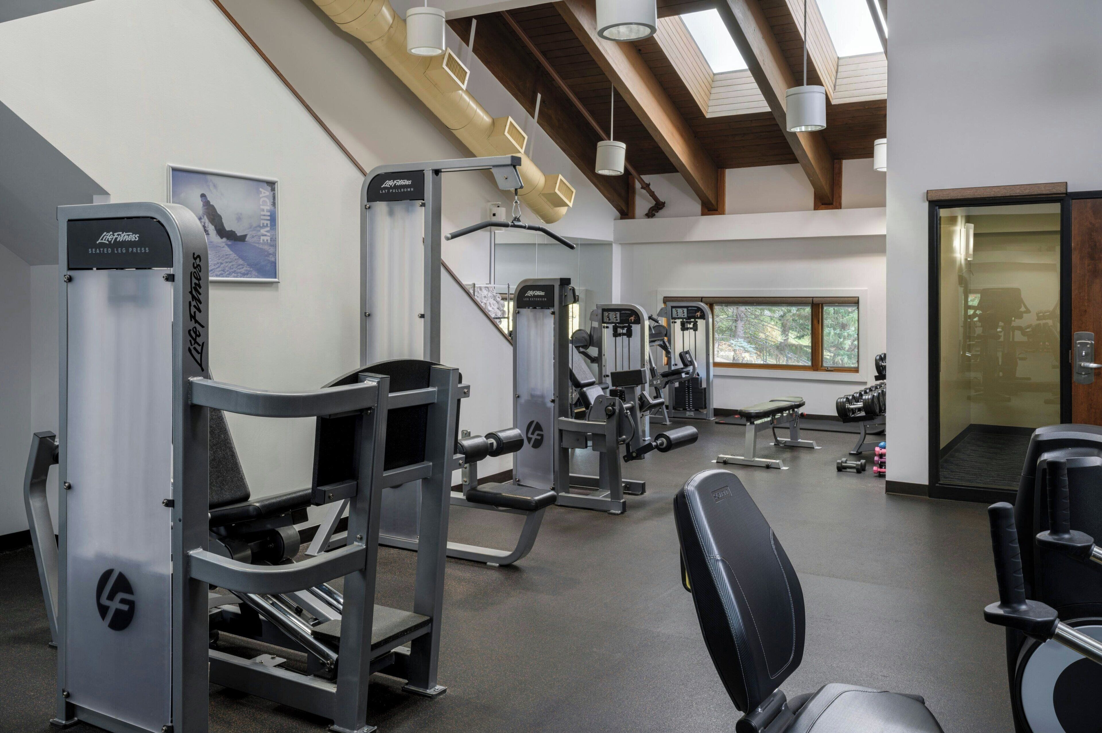 Une salle de sport équipée de divers appareils d’exercice, d’un banc et d’haltères.