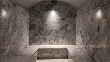 Experience the serenity of this bathroom with a curved ceiling and marble walls, featuring two benches for comfortable seating.