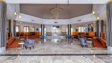 A spacious lobby with a central seating area, a World Bar, and a modern chandelier.
