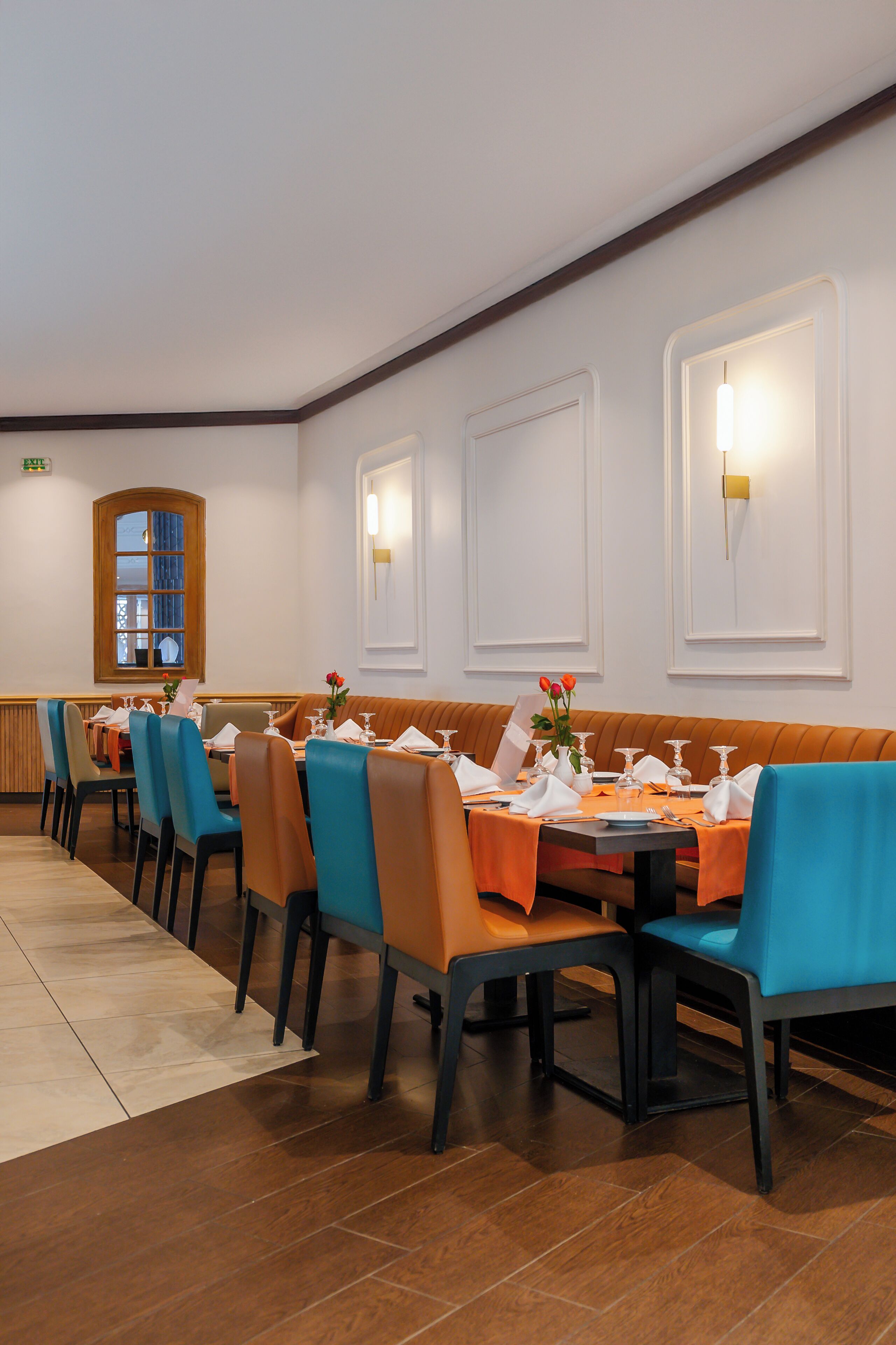 En restaurant med en lang disk, flere borde og siddepladser i båse. Borde og stole er dækket til spisning.