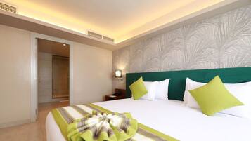 A hotel room with a large bed, a nightstand, a wall-mounted lamp, and a door leading to a bathroom.