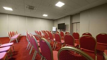 A conference room with rows of red chairs and a whiteboard.